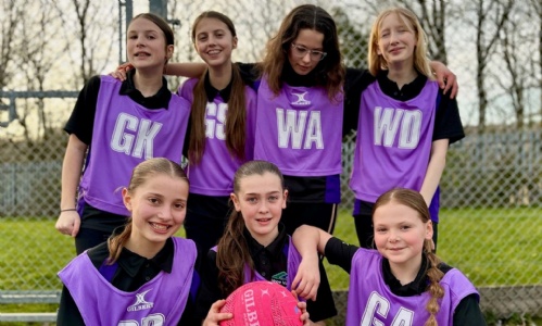 Year 7 Netball Team in purple bibs, smiling on the court